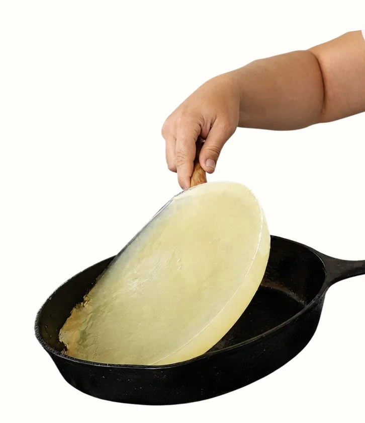 Hand lifting a disc of solidified oil out of a pan