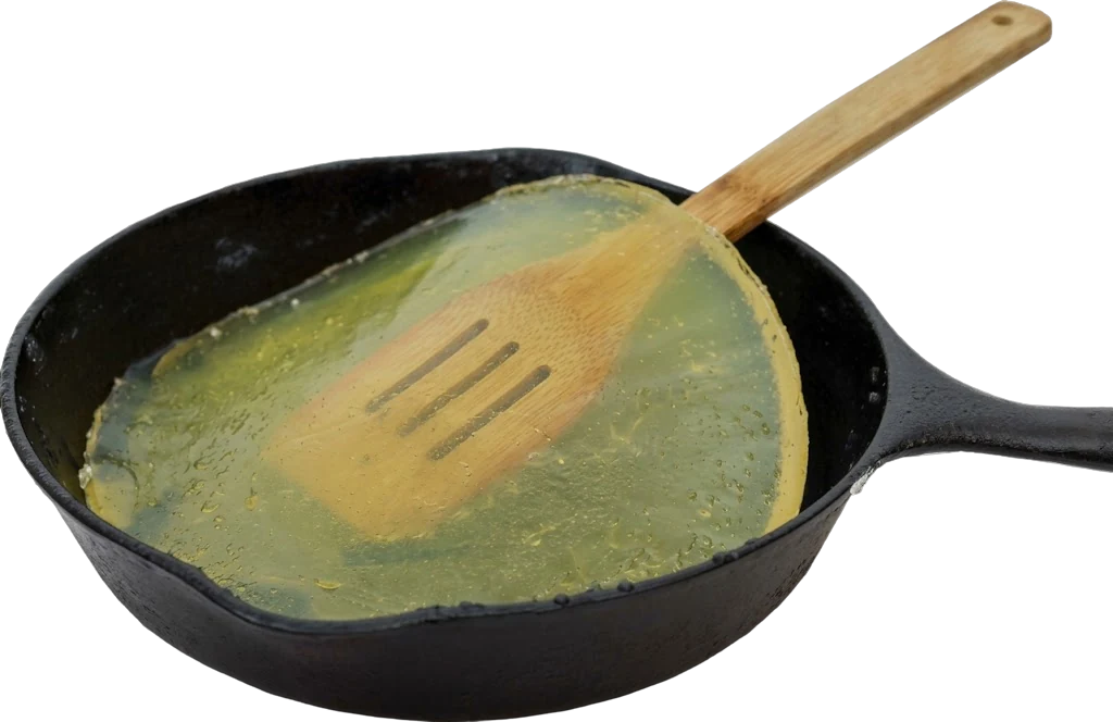 Cast iron pan of solidified cooking oil lifted with a wooden spatula